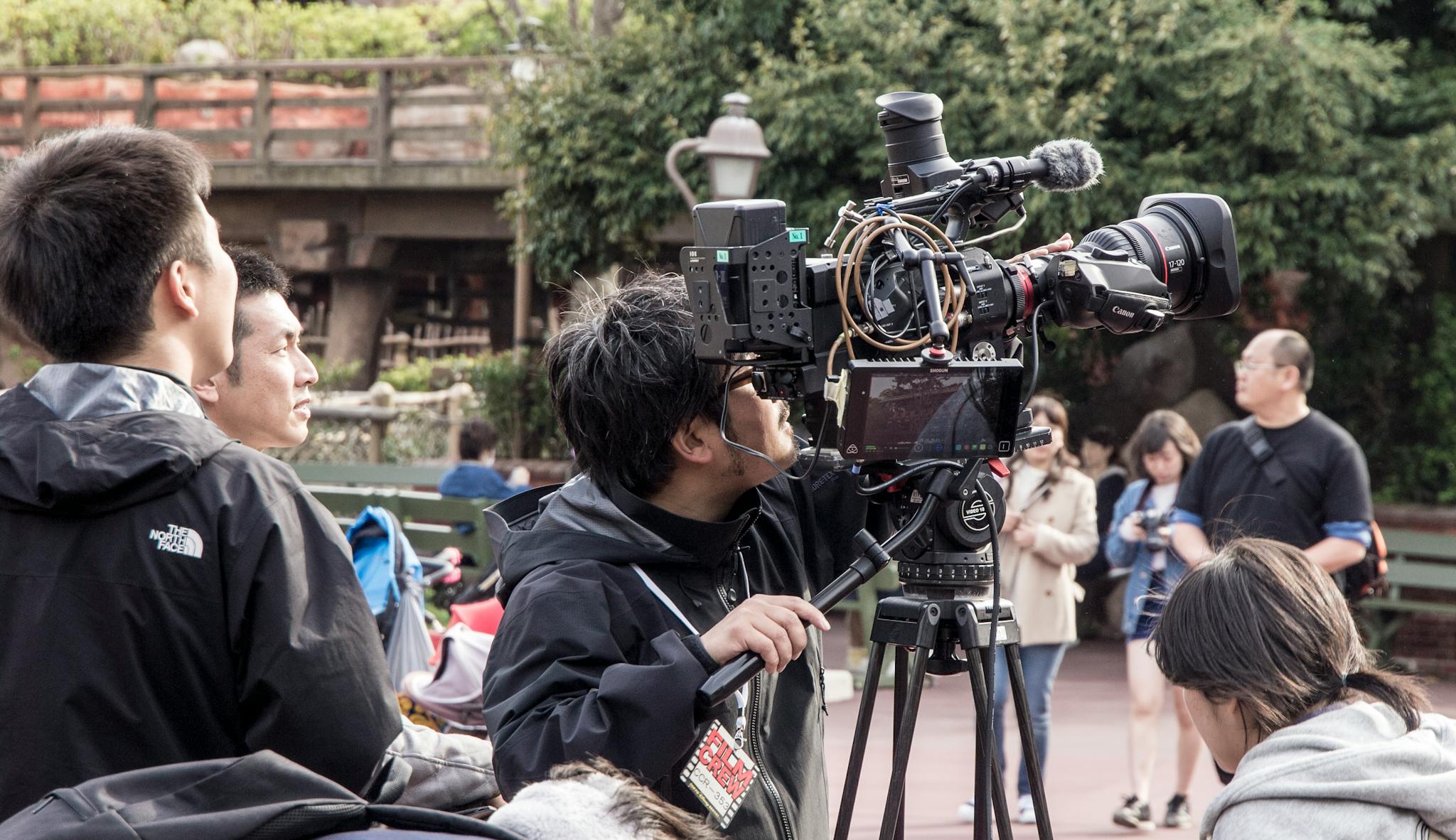 Film crew working with advanced camera equipment outdoors. Capturing footage in natural daylight.